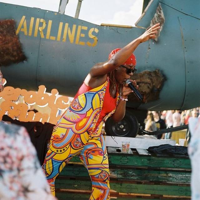 Performer in a patterned catsuit on stage in front of an airplane prop